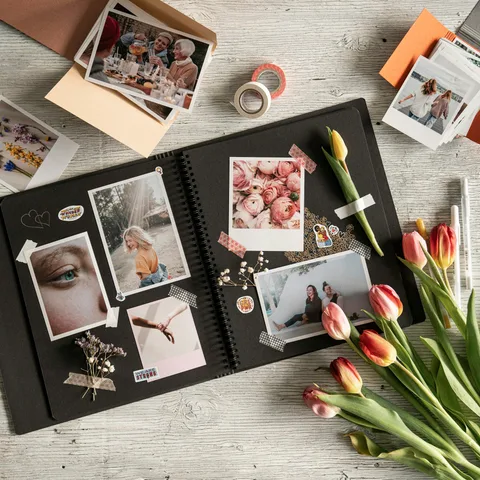 An open scrapbook with printed photographs, decorative tape, and tulips.